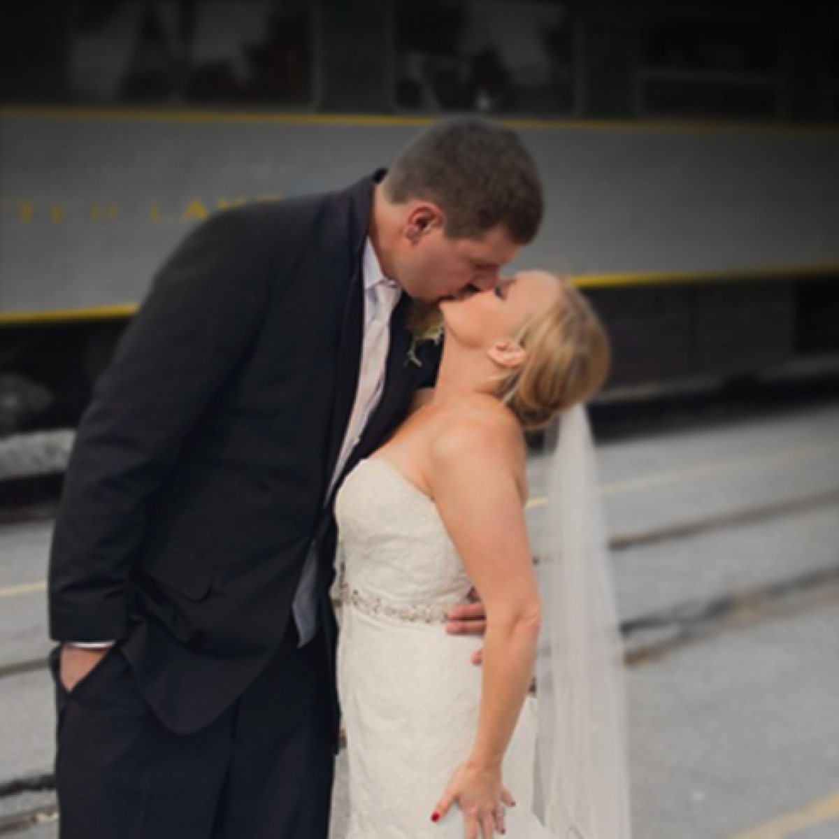 bride and groom kissing outside train