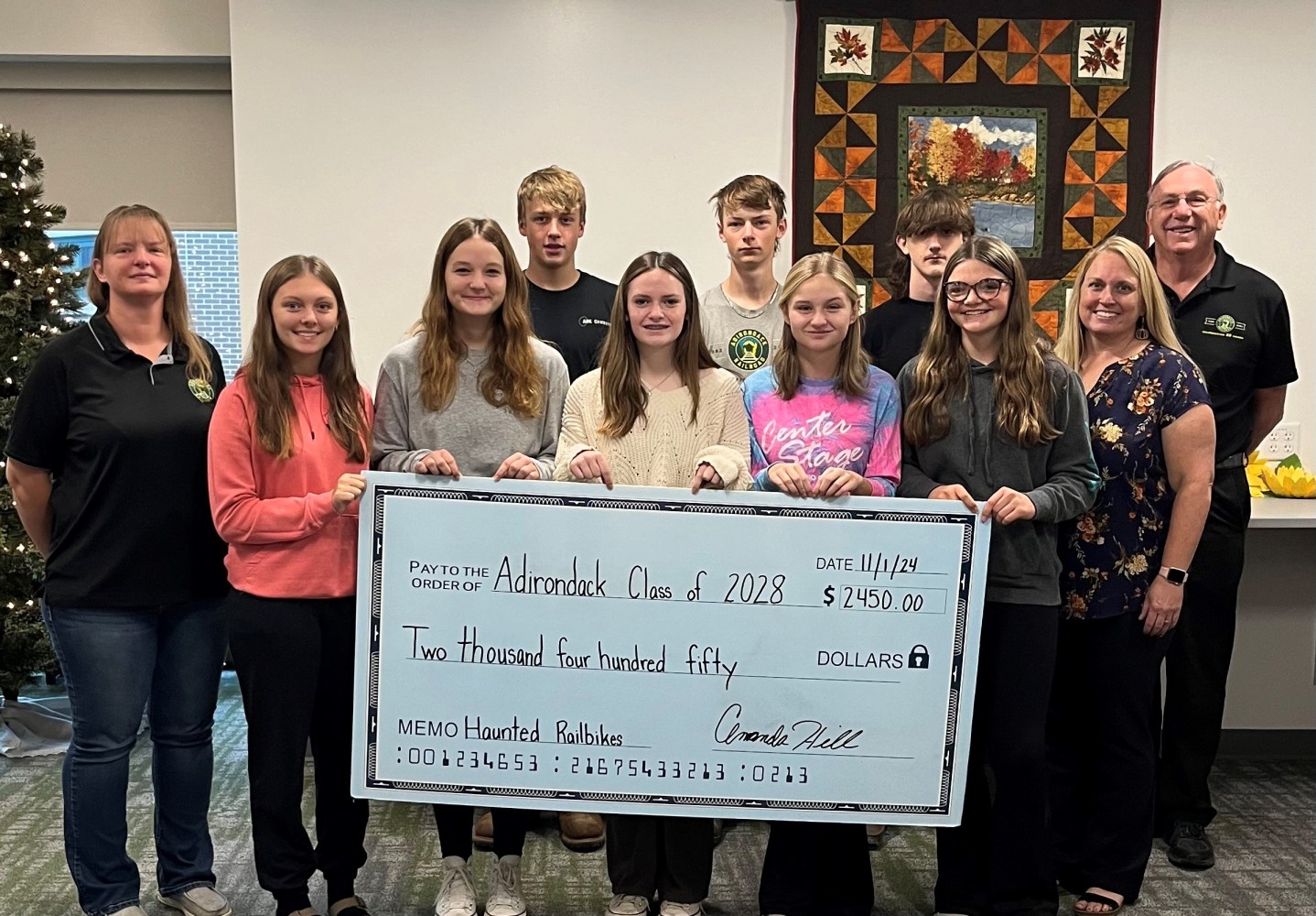 a group of people posing for a photo. Adirondack Railroad presented 2 checks, one to the class of 2028 and one to the class of 2026 at the Adirondack Central School. Each class received $2,450.