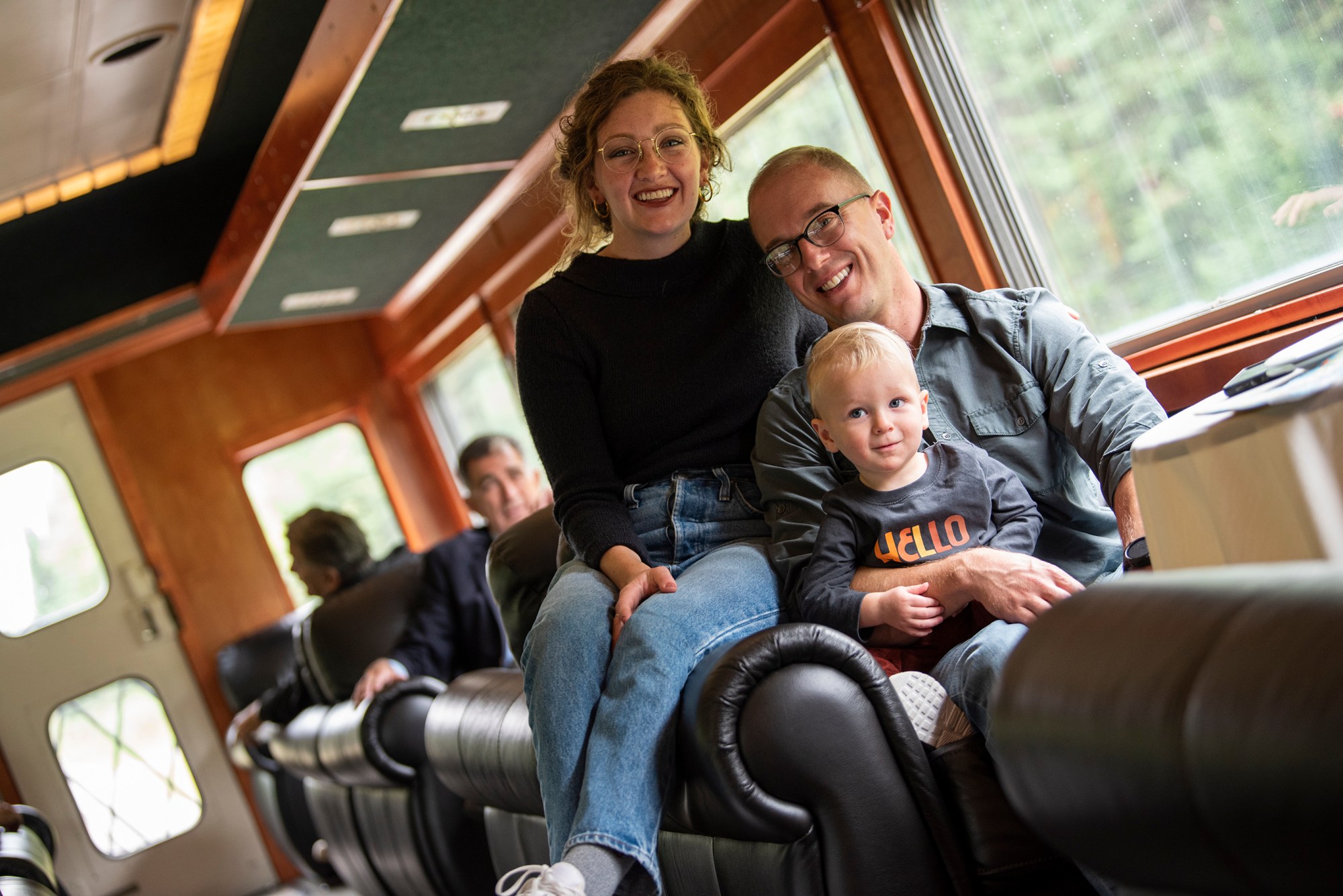 Family sitting together on a train seat with window view.