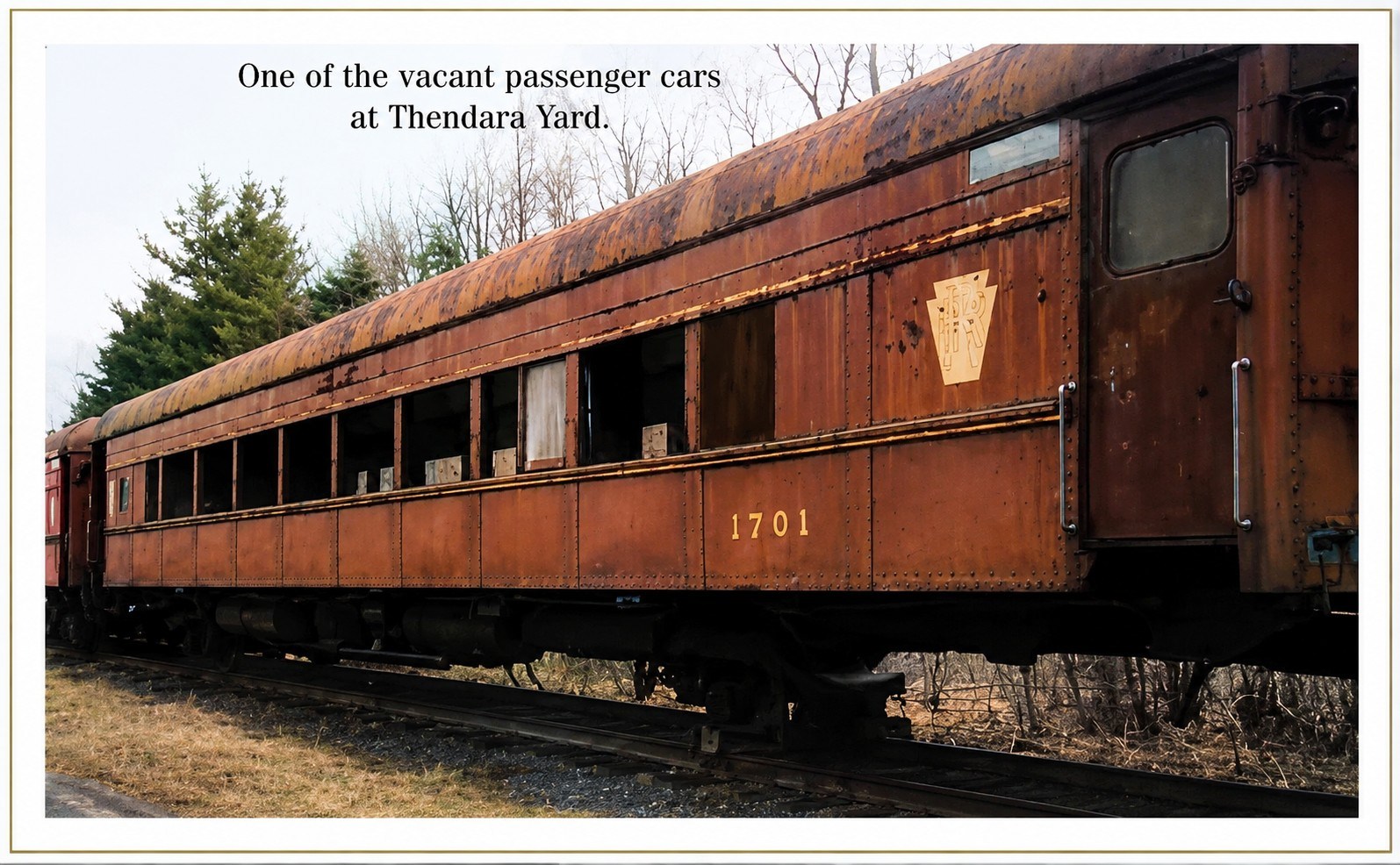 Rusty train car labeled '1701' in a wooded area with text: 'One of the vacant passenger cars at Thendara Yard.'