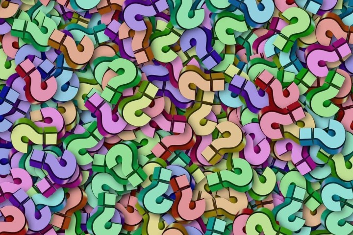 Colorful array of overlapping 3D question marks on a flat surface.