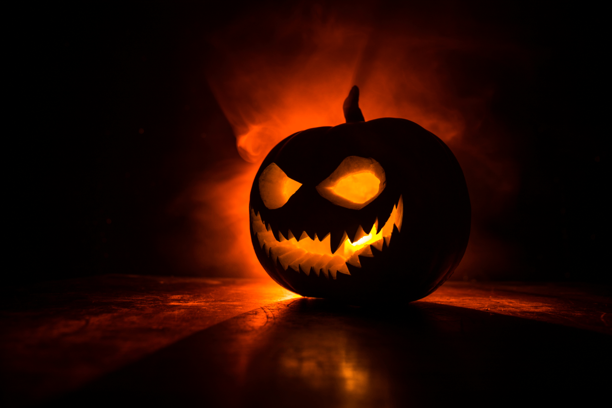 Glowing jack-o'-lantern with sinister expression and fiery background.